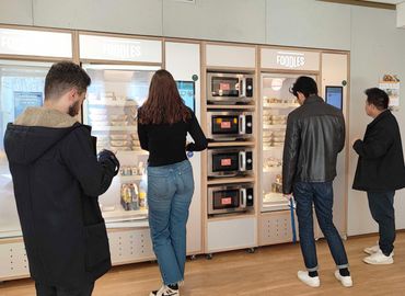 Multiple persons in front of fridges.